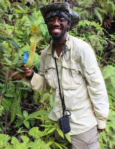 Dr. Kadeem J. Gilbert smiles while holding a Nepenthes mindanaoensis pitcher plant while in the field on Mount Hamiguitan in the Philippines.