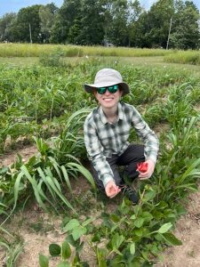 Robin Waterman smiling, kneeling in an agricultural field