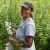 Lindsey Kemmerling stands among tall plants with narrow green leaves, taking notes.