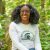 Portrait of Dr. Asia Dowtin, seated in a forested area with trees and shrubs in the background.